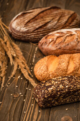 Wall Mural - selective focus of fresh baked bread loaves with spikelets on wooden surface