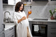 © alfa27 - portrait of happy pregnant lady drinking fresh juice in the kitchen, attractive female smile, expect baby. healthy nutrition for pregnant female
