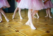 Faceless Young Ballet Dancers (teenagers) In Pointe Wearing Beautiful Pink Costume/tutu Ready To Perform On Wooden Floor. 