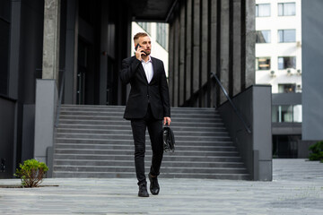 Wall Mural - A young man in strict clothes with a bag in his hands goes down