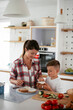 © JustLife - Mother and son making breakfast. Mother and son eating sandwich in kitchen...