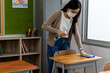 © JR-50 - An Asian woman teacher sprayed alcohol and used a cloth to clean students' desks to prevent the coronavirus outbreak in schools.