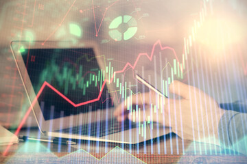 Double exposure of man's hands holding and using a digital device and forex graph drawing. Financial market concept.