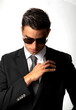 Attractive young man in business suit and sunglasses looking straight down on white background