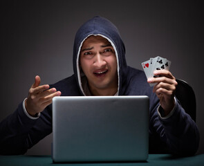 Wall Mural - Young man wearing a hoodie sitting in front of a laptop computer