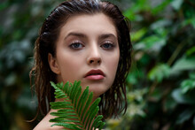 Beautiful Young Woman With Perfect Skin And Natural Make Up Posing Front Of Plant Tropical Green Leaves Background. Teen Model With Wet Hair.  SPA And Skincare.