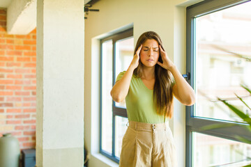 young pretty woman looking concentrated, thoughtful and inspired, brainstorming and imagining with hands on forehead