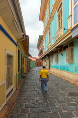 Wall Mural - Ecuadorian man walking in a colorful colonial style street, Guayaquil, Ecuador.