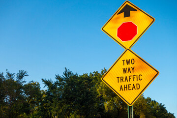 double street sign reading two way traffic ahead sign with exagonal stop sign icon and arrow