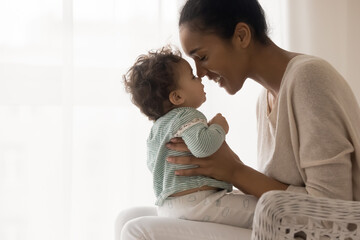 Wall Mural - smiling young african american affectionate mommy holding on laps little cute toddler baby, touching