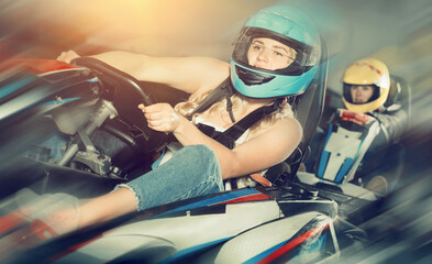 Portrait of female racer in helmet driving kart on a track