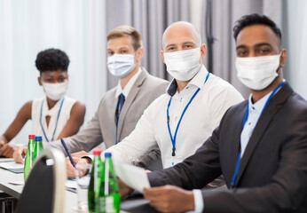 Wall Mural - business and education concept - group of people wearing face protective medical mask for protection from virus disease at at meeting or international conference