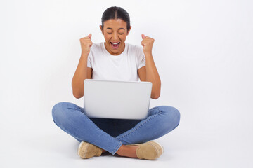 Wall Mural - Caucasian brunette woman rejoicing her success and victory clenching her fists with joy. Lucky woman being happy to achieve her aim and goals. Positive emotions, feelings.