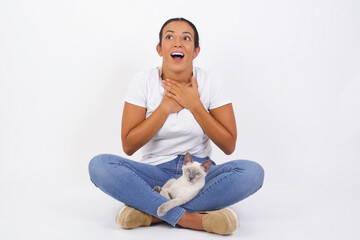 Wall Mural - Happy business woman standing and smiling isolated on gray studio background has hands on chest near heart. Young emotional woman. Human emotions, facial expression concept. Front view.