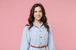 Smiling charming beautiful attractive pretty young brunette woman 20s wearing casual blue shirt dress posing standing looking camera isolated on pastel pink colour background, studio portrait.