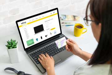 Wall Mural - Woman shopping online with laptop during the black monday or cyber monday holidays. Credit card in right hand concept. Modern ecommerce web site design on display
