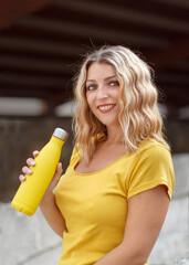 Young woman holding yellow reusable bottle