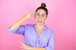 Young beautiful woman wearing glasses over isolated pink background Shooting and killing oneself pointing hand and fingers to head like gun, suicide gesture.