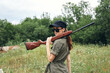 © SHOTPRIME STUDIO - Woman With shotgun sunglasses green jumpsuit black cap