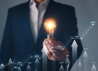 Businessman holding illuminated lightbulb with forex trading and financial market . Concept of innovation financial market.