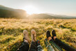 © Serhii - Legs of traveler family with child sitting on a high mountain. Close Up. People enjoying the sunset in mountains. The concept of family travel, adventure, and tourism. Hiking autumn vacations outdoor.