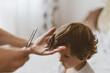 © Анастасія Стягайло - Father cuts her son hair in the room. Family during quarantine, Scissors and a comb in male hands