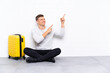 © luismolinero - Young handsome man sitting on the floor with a suitcase pointing with the index finger a great idea