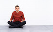 © luismolinero - Young handsome man sitting on the floor standing and looking to the side