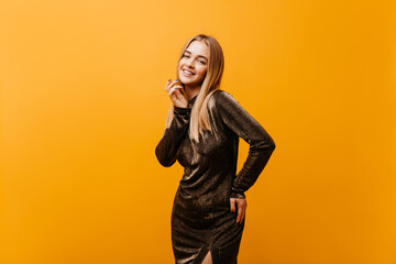 Wall Mural - Amazing fair-haired girl in elegant dress smiling to camera. Indoor shot of lovely caucasian model with happy face expression.