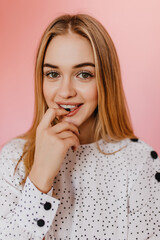 Wall Mural - Glamorous girl with big green eyes looking to camera. Indoor photo of blithesome young woman playfully posing on pink background.