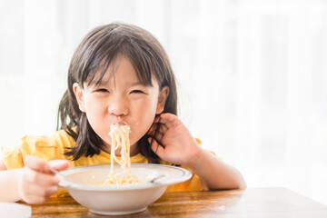 Wall Mural - Hungry face and enjoy eating concept.Little asian girl enjoy eating with spaghetti carbonara with cheese on a plate in lunch time at restaurant.kid eating pasta.Delivery food, Delicious face.