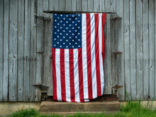 American Flag Hanging On Door Of Old Gray Wood Barn In Rural Country, Farm, Building, Outdoor, Ranch, Patriotism, America, Usa, Patriotic