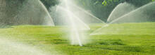 Irrigation System Watering The Green Grass, Blurred Background