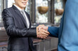 © amorn - Businessman shaking hands, wearing office suit, standing meeting and congratulation with partnership