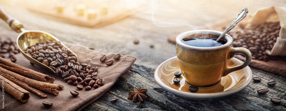 Obraz na płótnie A cup of aromatic black coffee and coffee beans on the table. Morning Coffee Espresso for breakfast in a beautiful blue cup. w salonie
