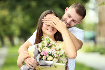 Poster - Happy young couple with bouquet of flowers in the park