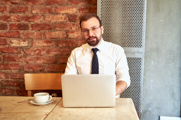 The employee sitting outside the office continues to work outside. man working in the office with white shirt and tie.