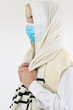Orthodox Jewish man praying with prayer shawl, tallit, over his head, wearing protective mask against the covid-19 pandemic.