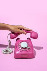 Layout made of pink telephone on blue background. Retro vintage 60's and 70's aesthetic with summer shadows. Flat lay.