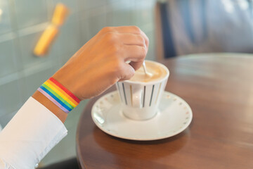 woman's hand with lgtbi bracelet with cup of coffee