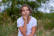 © NataliaSavilova - Pensive sad teenager girl looks to the side. Portrait in the park outdoors. Emotions, feelings concept. Blurred background