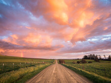 View Of Dirt Road Passing Through Fields During Sunset