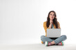 © New Africa - Pensive young woman sitting with laptop on white background