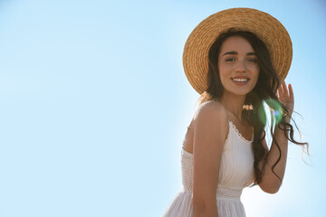 Wall Mural - Happy young woman with beach hat against blue sky on sunny day