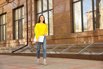 Poster - Happy young woman with laptop walking outdoors