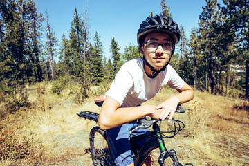 A teen boy takes a break frm riding on trails in north Idaho.