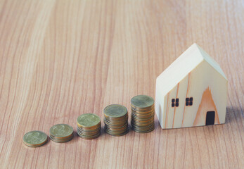 Toy house placed beside the coin on the wooden floor.