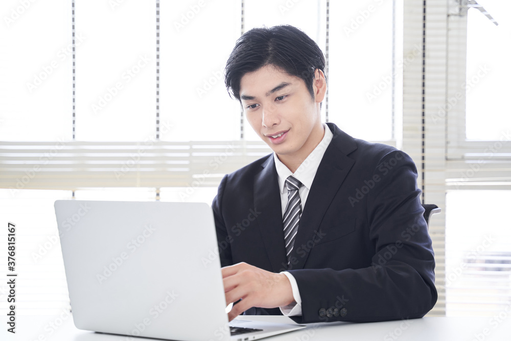 オフィスで笑顔でノートパソコンを操作する日本人男性ビジネスマン Wall Mural Mapo