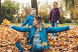 © Strelciuc - Caucasian mother with glasses is playing in leaves with her son and daughter during a walk in park