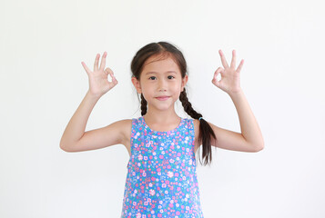 Wall Mural - Cheerful asian little kid girl showing finger ok symbol sign language isolated over white background